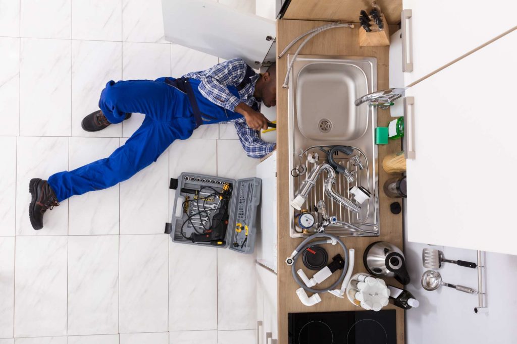 Reline-A-Pipe Technician cleaning a blocked drain in a kitchen